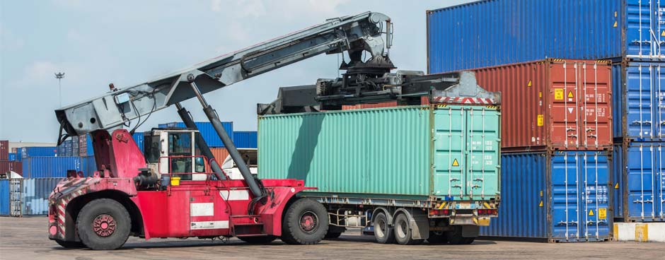 Container handler moving cargo boxes at a port.