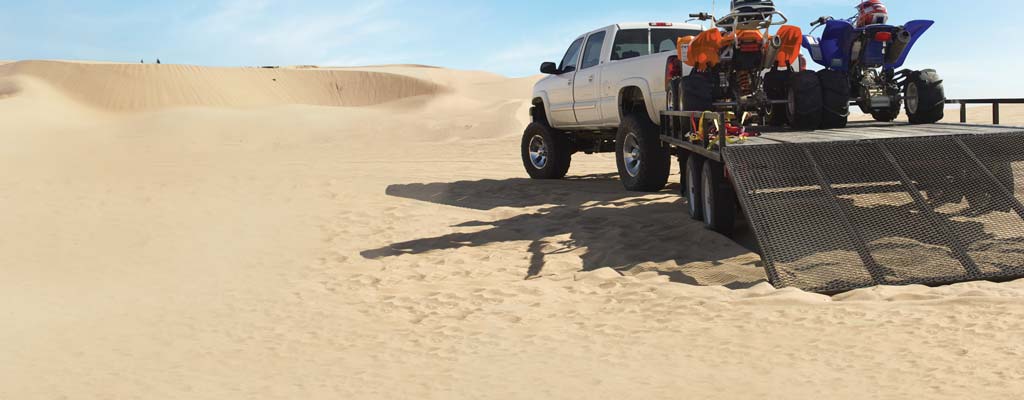 Truck with loaded trailer on sand dunes.