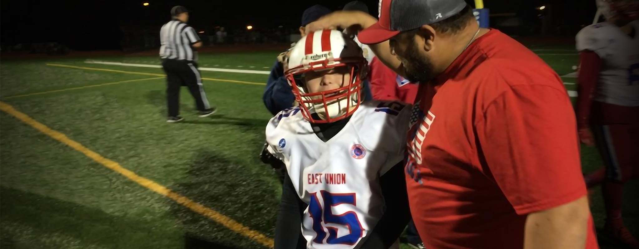 The East Union high school football coach pats a player on their head.
