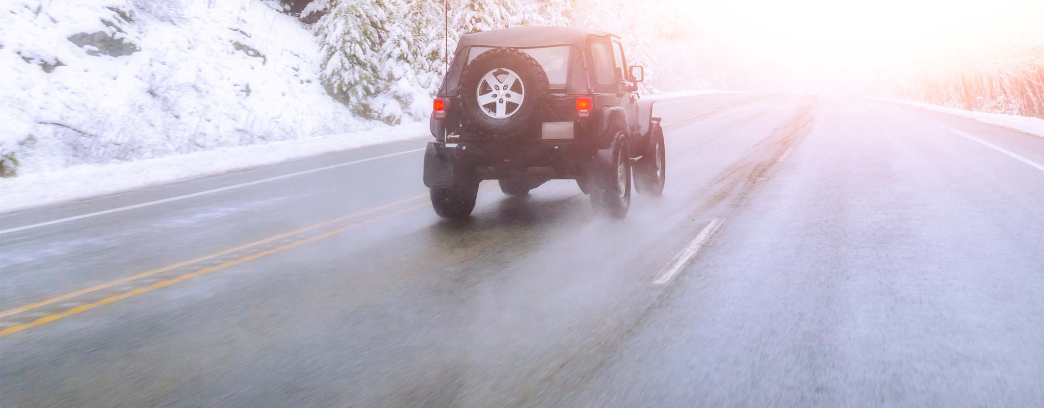 Jeep driving down winter roadway.