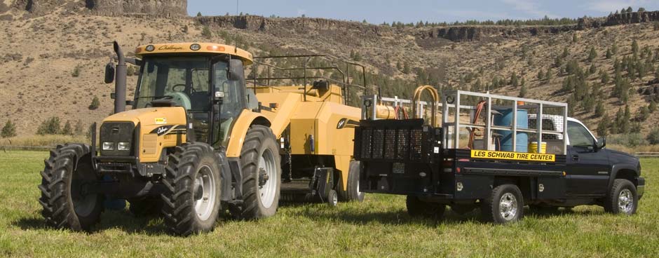 Les Schwab service truck in a field with a yellow tractor