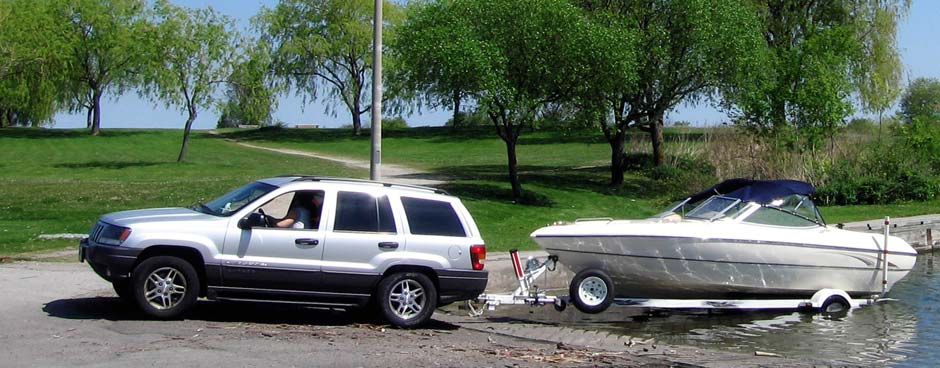 A Jeep Cherokee pulls a boat out of the water on a trailer.