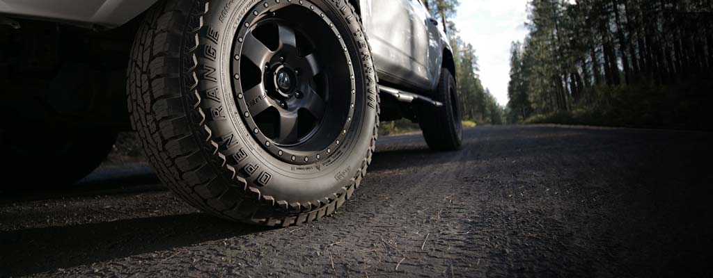 Closeup of a vehicle tire on a gravel forest road.