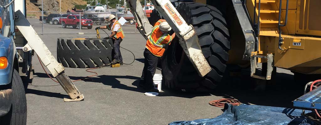 Les Schwab employees changing a giant tire.