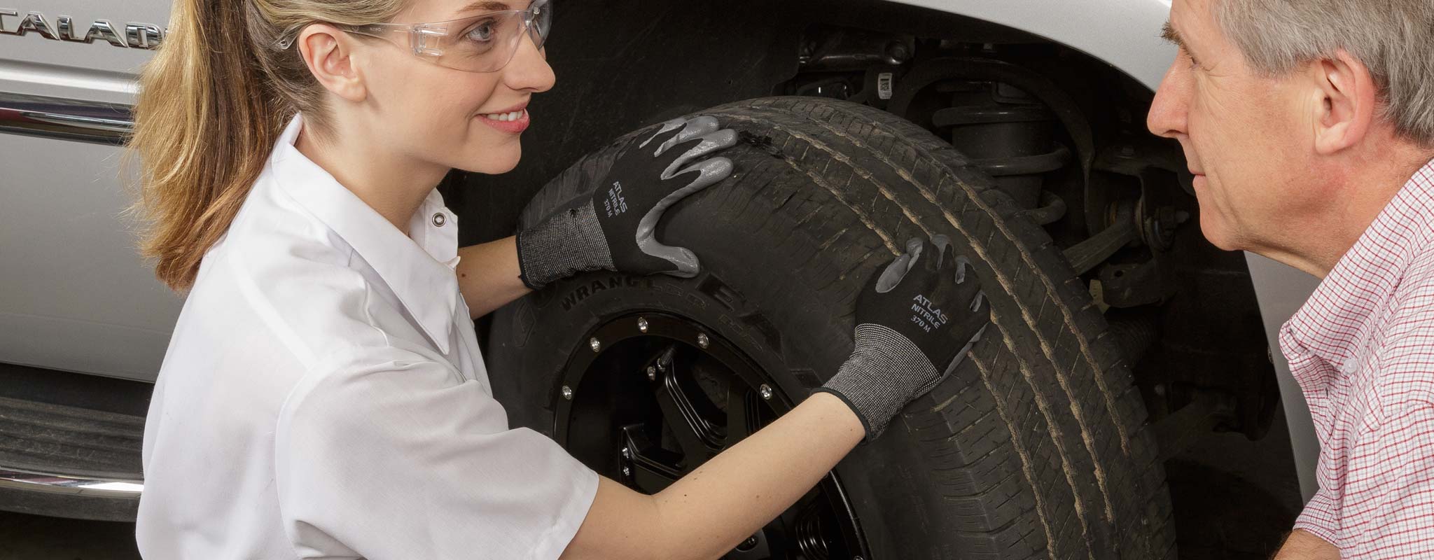 Female tire technician talking to a customer about his tire.