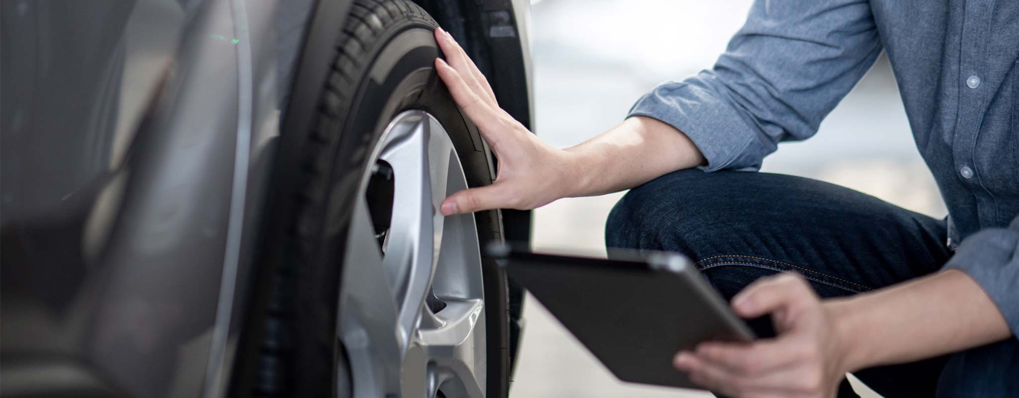 Person checking his tire with a tablet in his hand