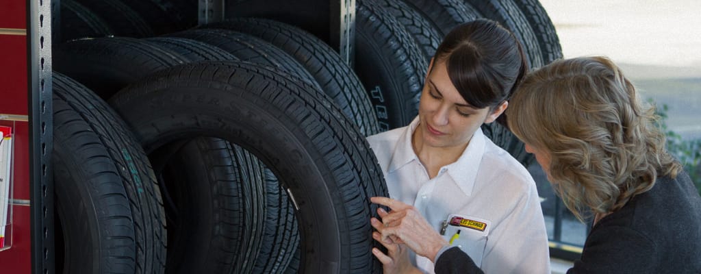 A wide shot of an employee showing tires to a female customer